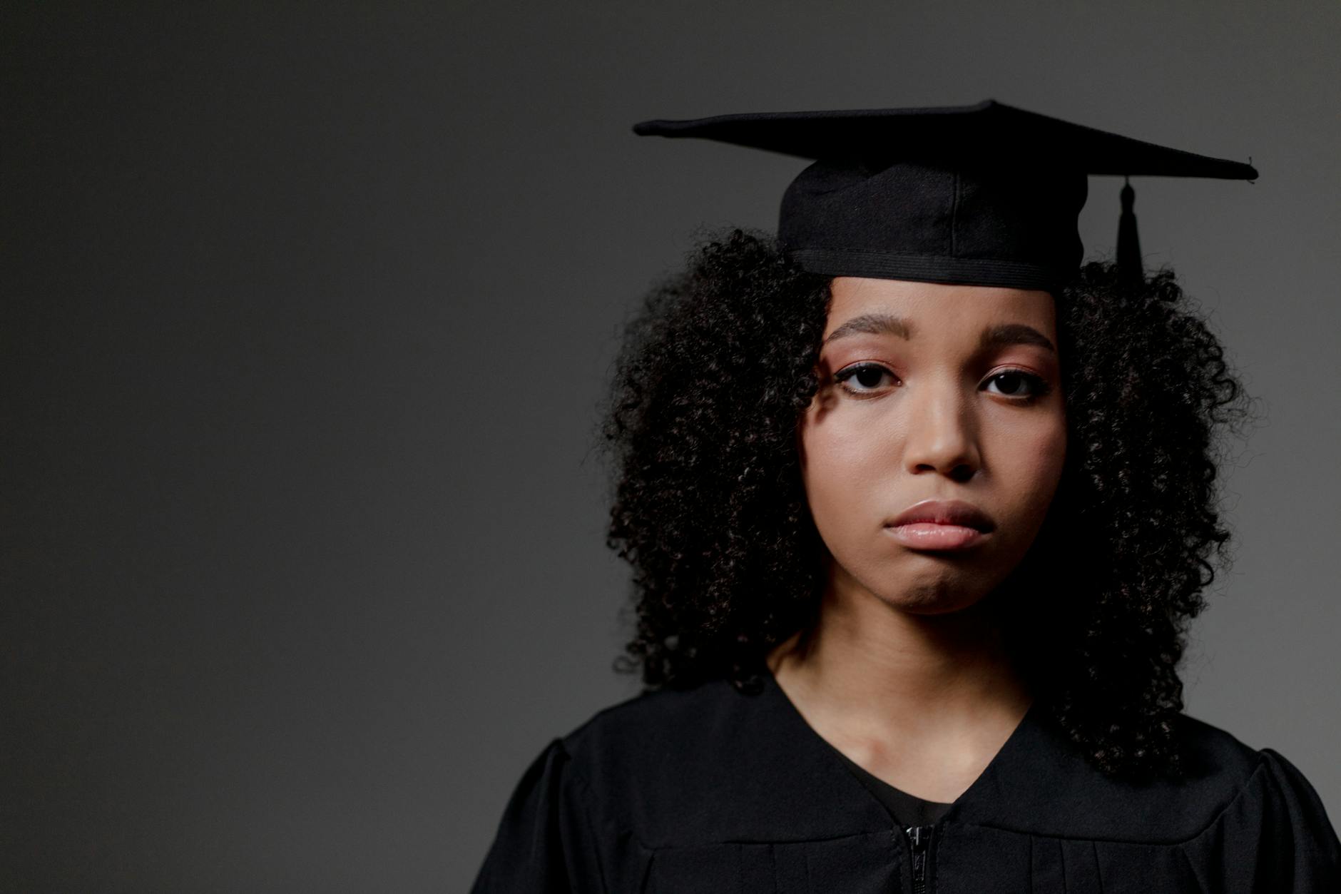 a sad black female student looking at camera and wearing square academic cap